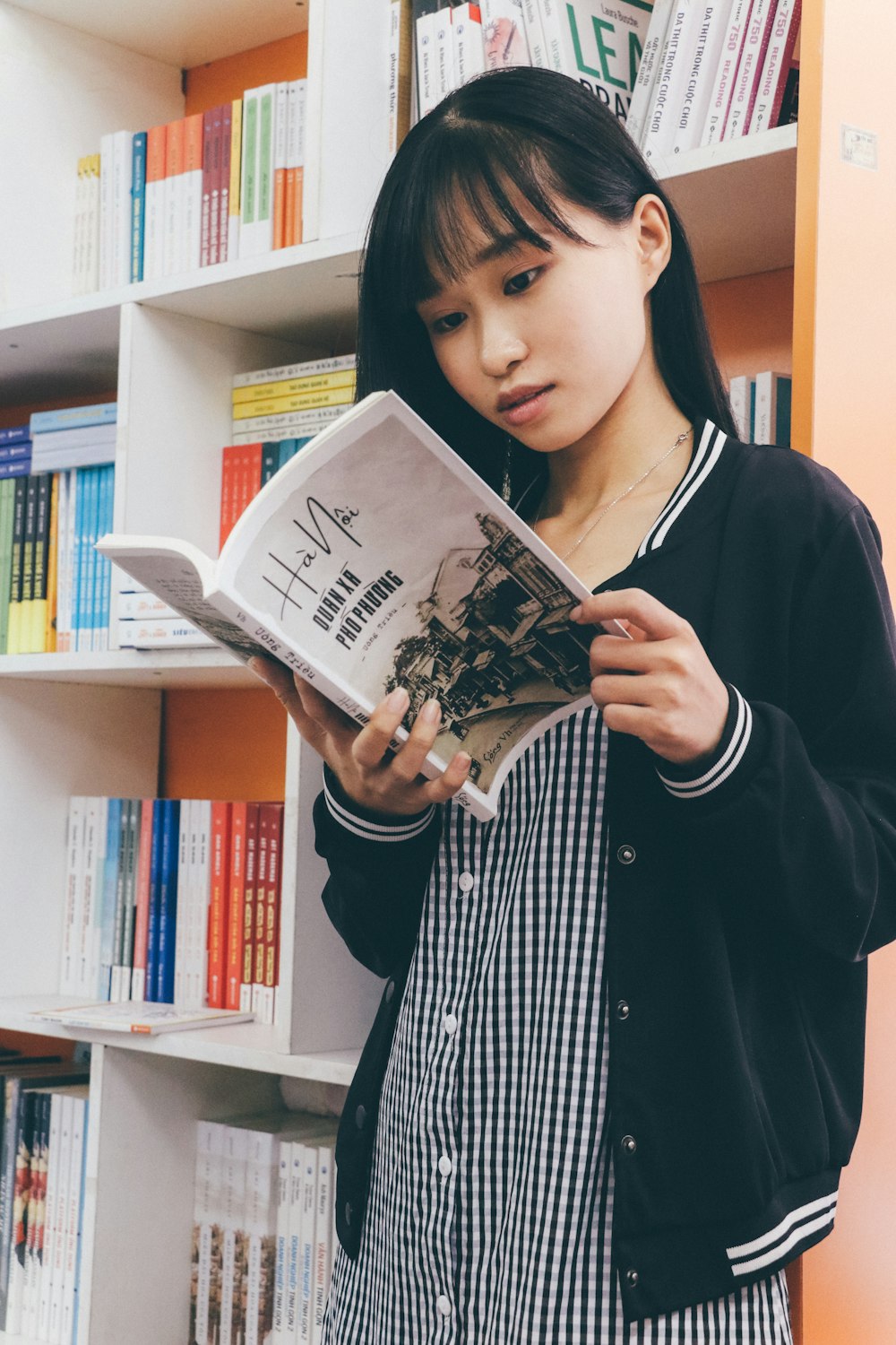 woman reading book wearing black and white jacket