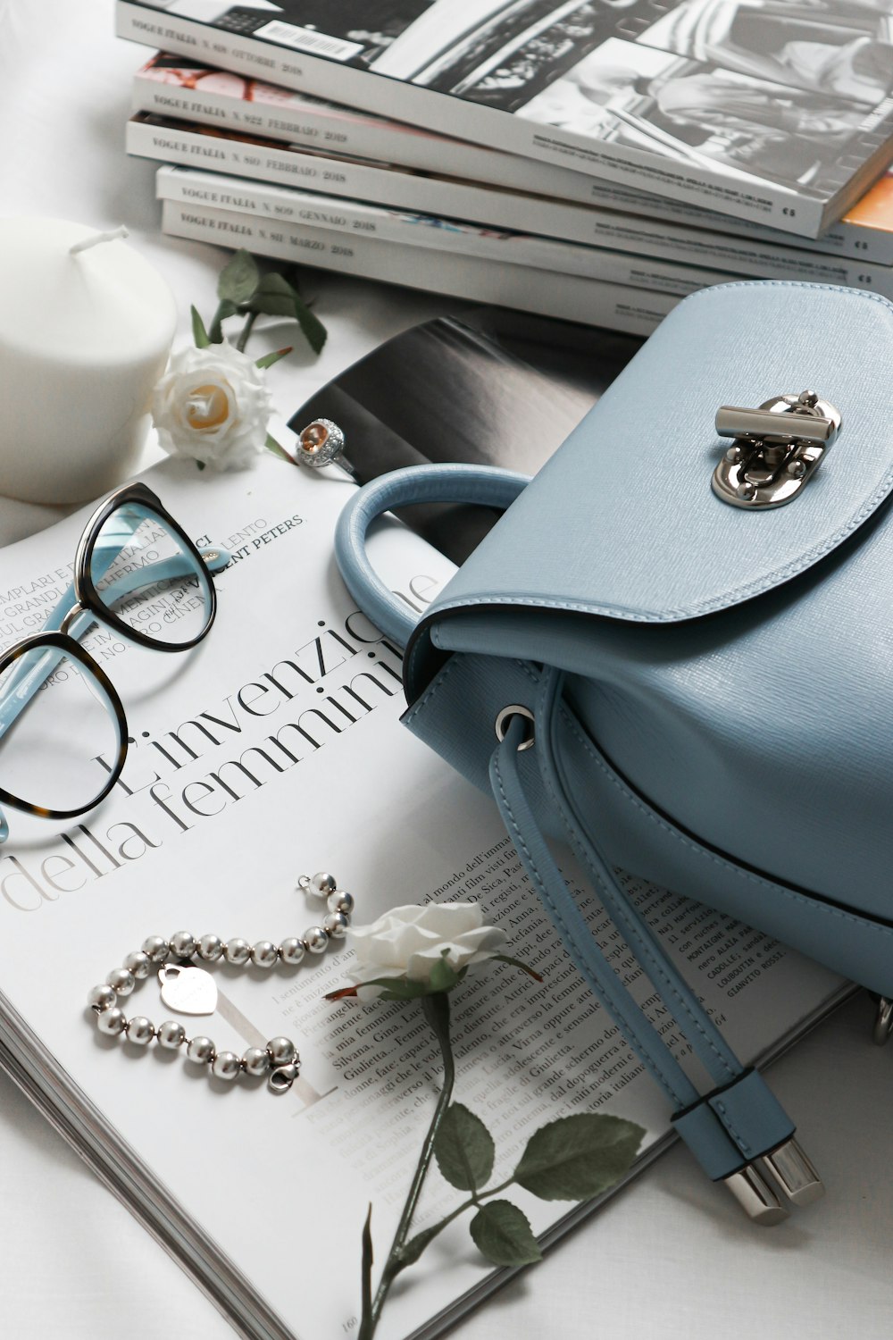 sac à main en cuir gris à côté des lunettes et des livres