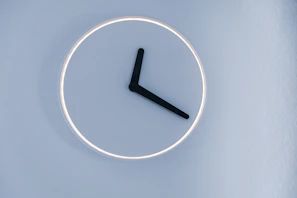 A minimalist digital clock displaying time in bright blue on a clean white wall