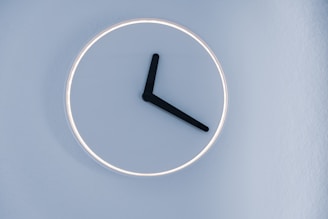 A sleek digital calendar clock mounted on a modern office wall, glowing softly.