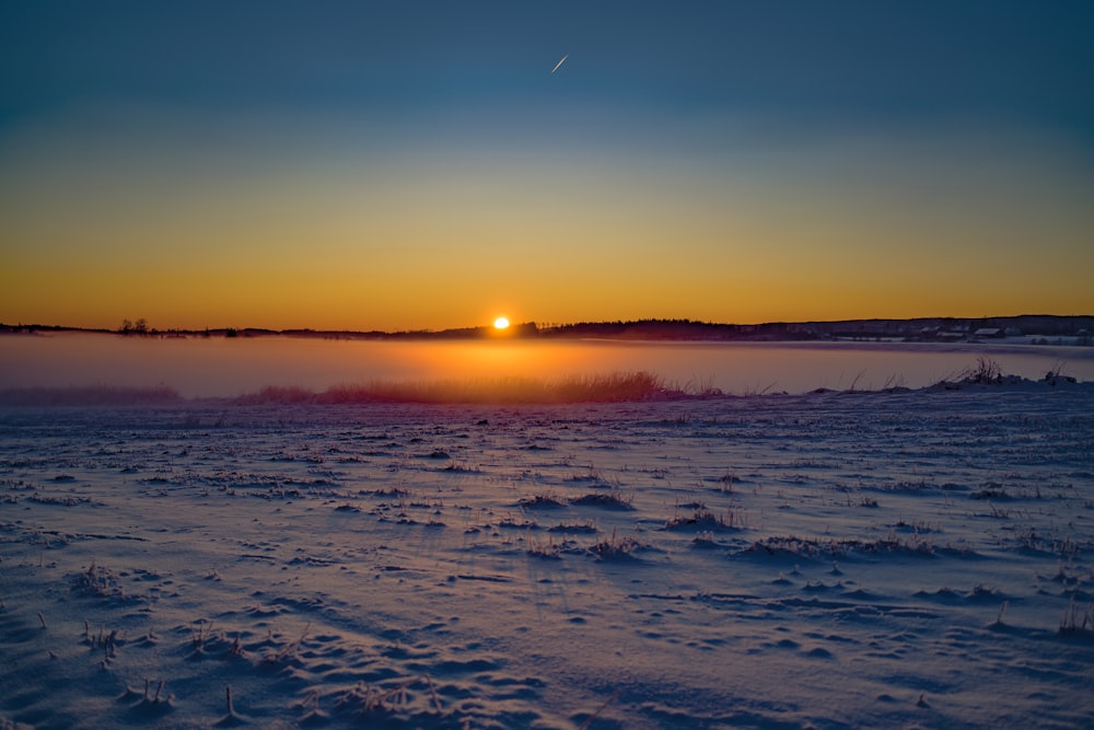 photography of snow-covered field during sunset