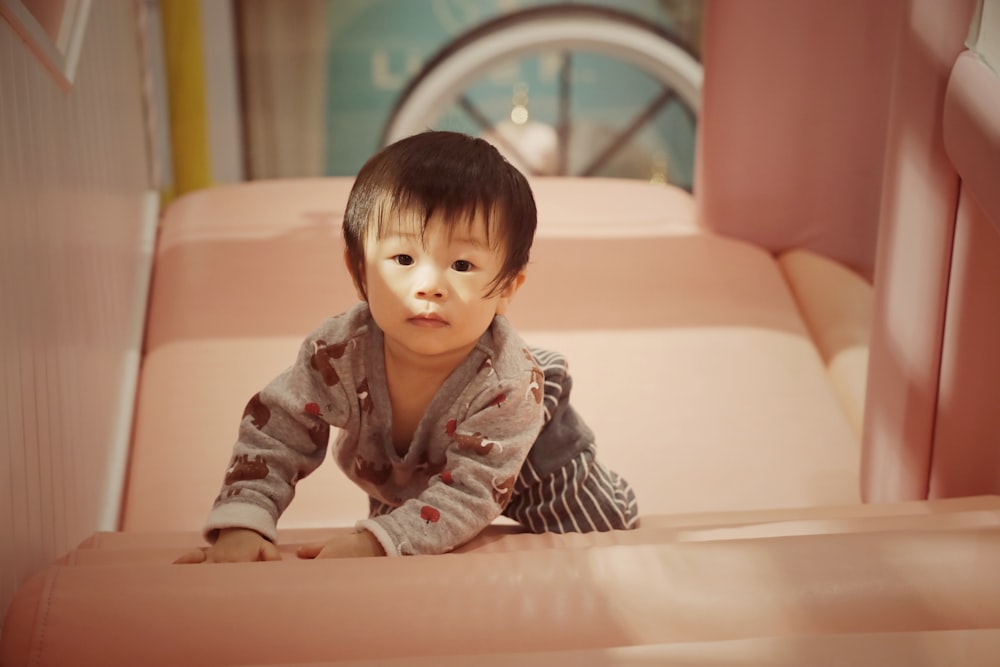 a small child sitting on a pink couch