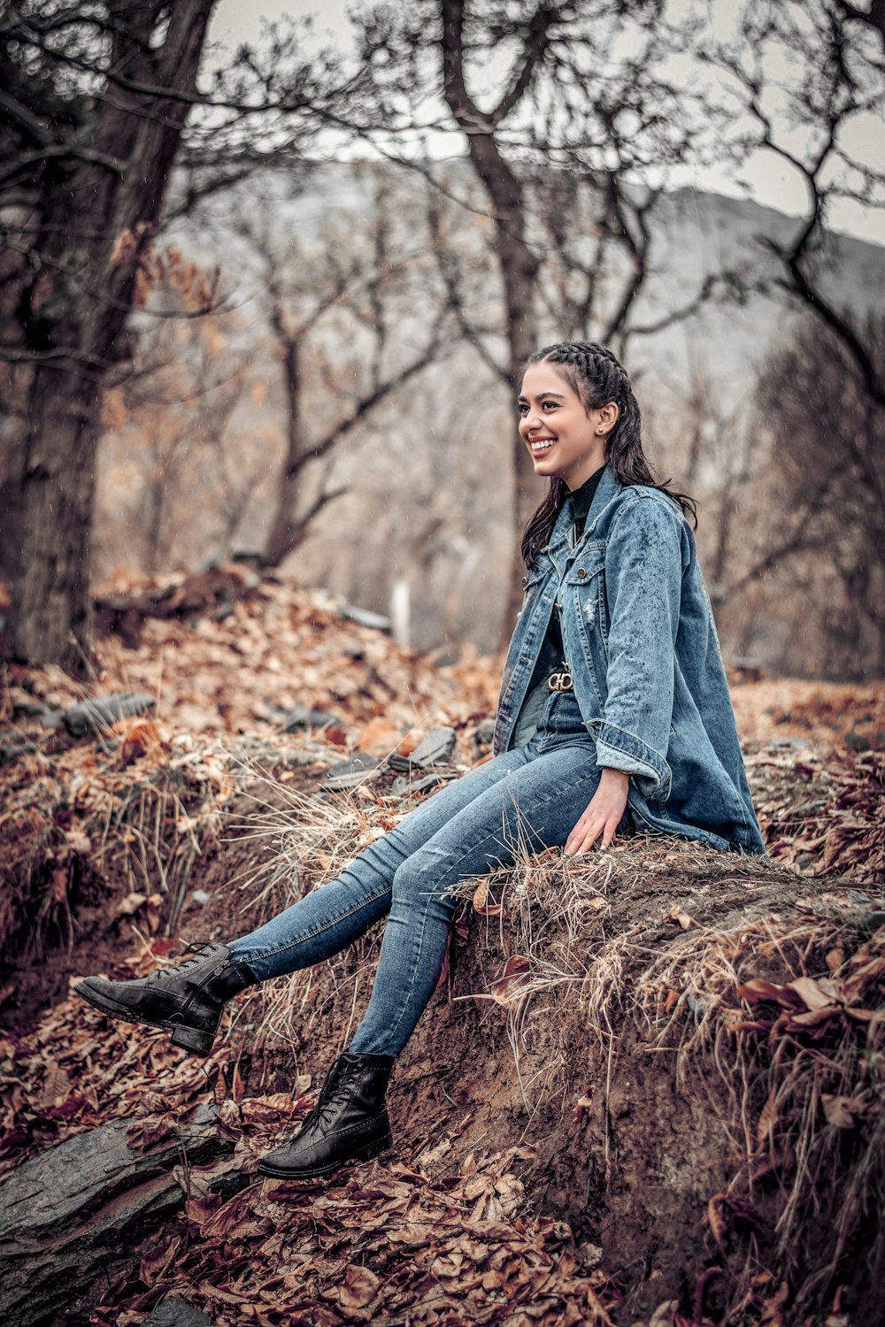 woman smiling and sitting on soil ground near trees