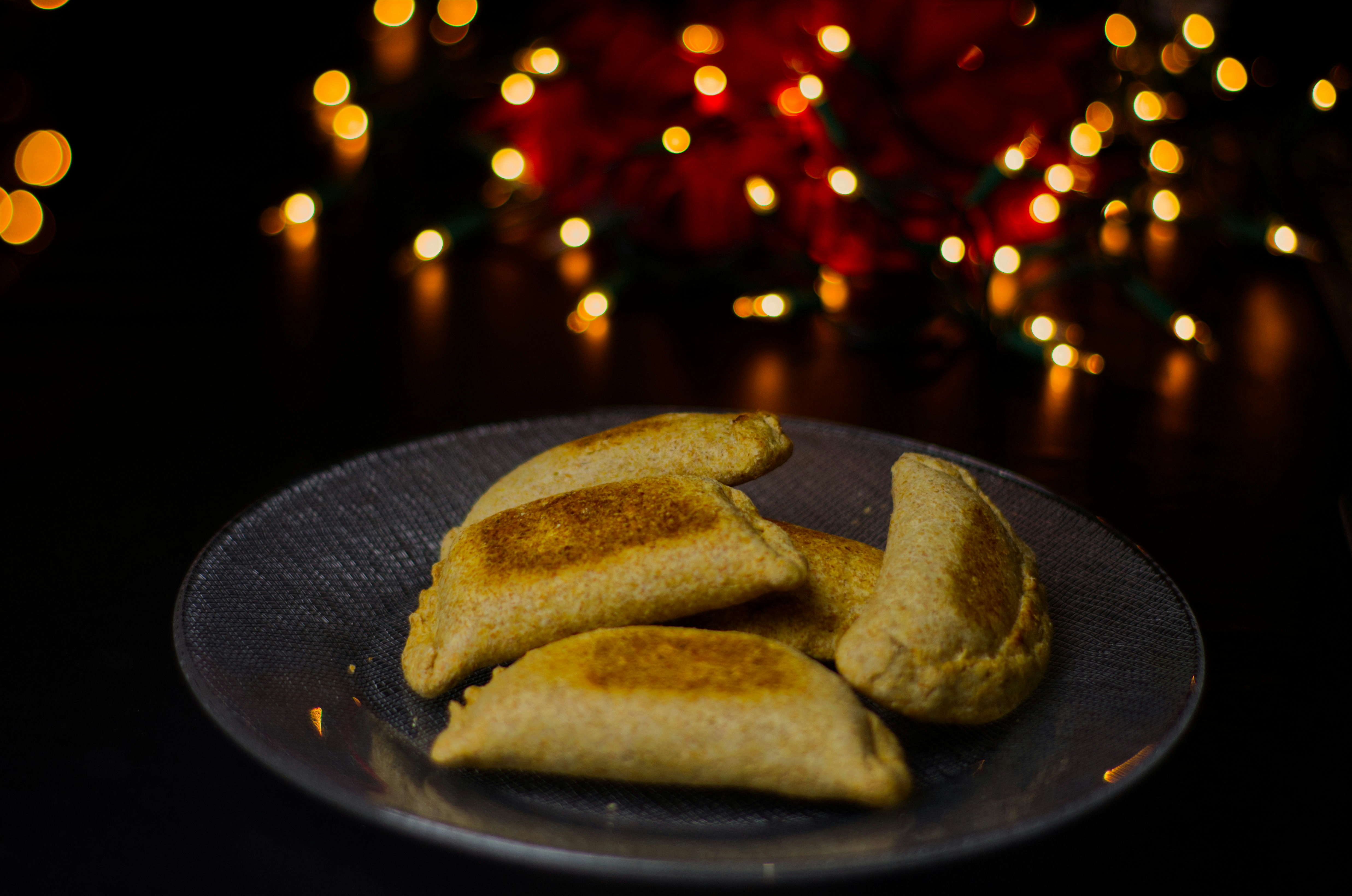 Rows of golden empanadas baking in oven, dark moody kitchen atmosphere, deep shadows