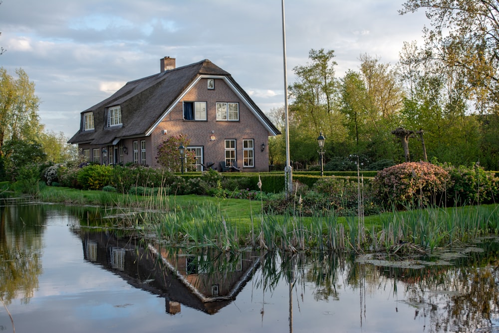 house on grass field near trees and body of water