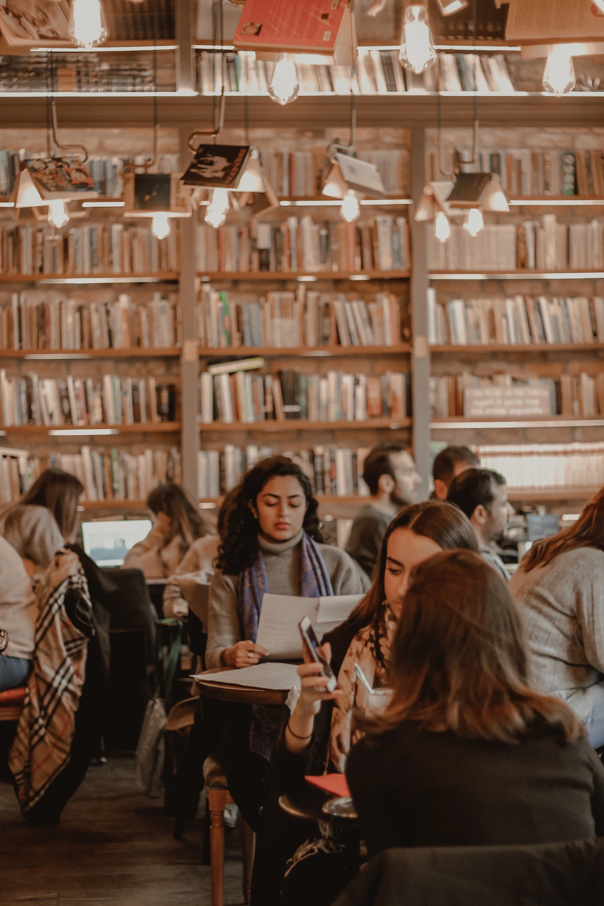 Students seated in a university library, heads down, focused