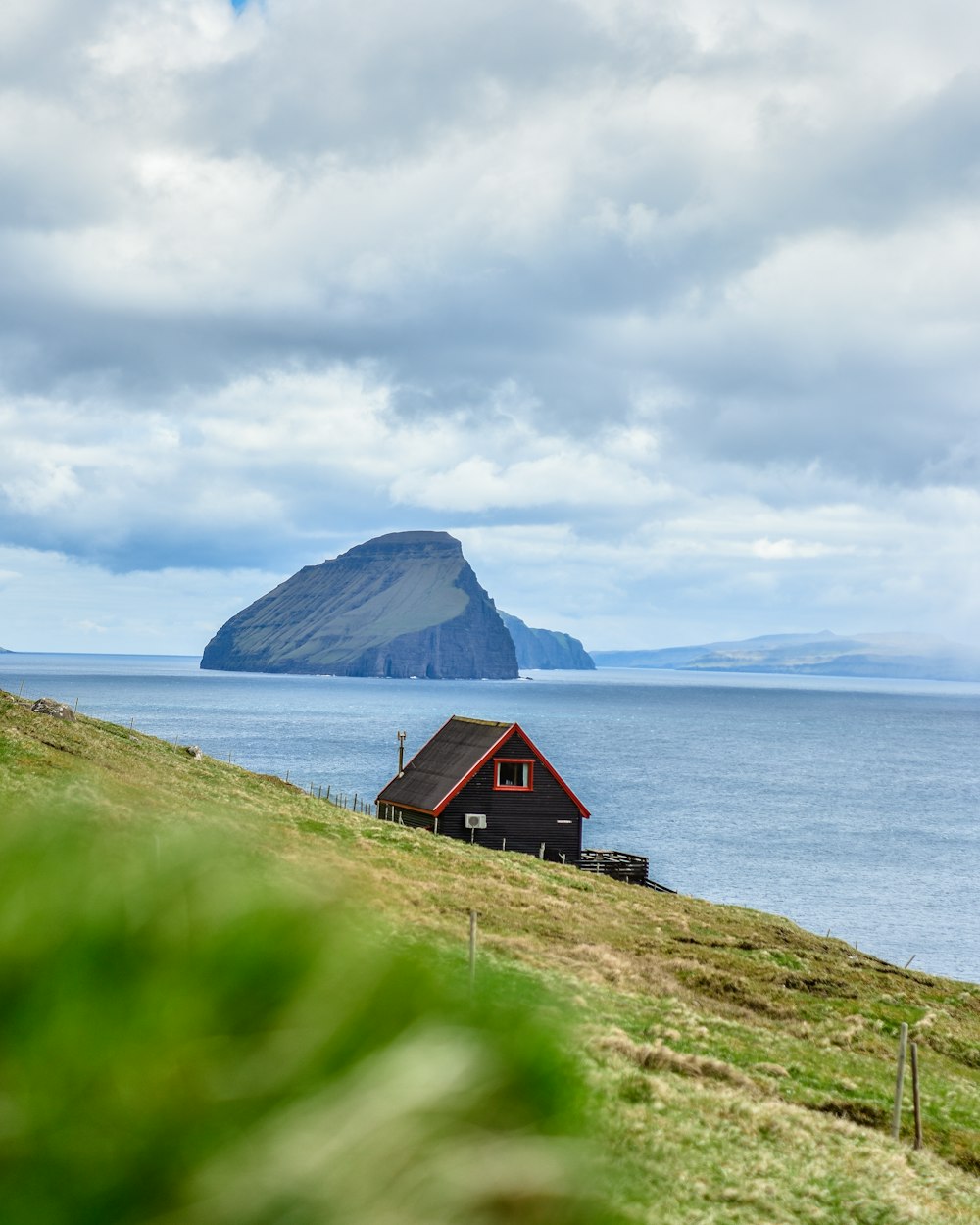 black cabin near body of water under cloudy sky