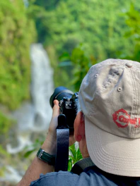 person taking photo of waterfall during daytime