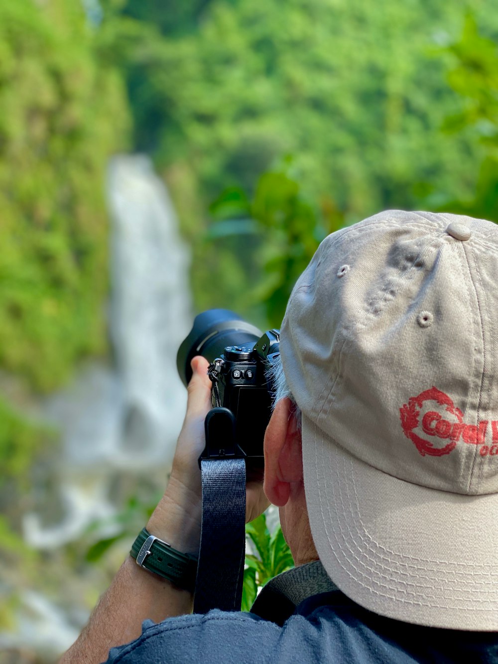 person taking photo of waterfall during daytime