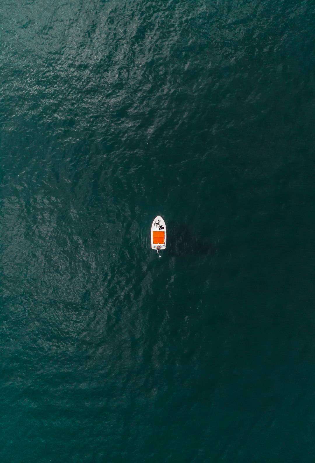 white and orange sailboat in the middle of ocean