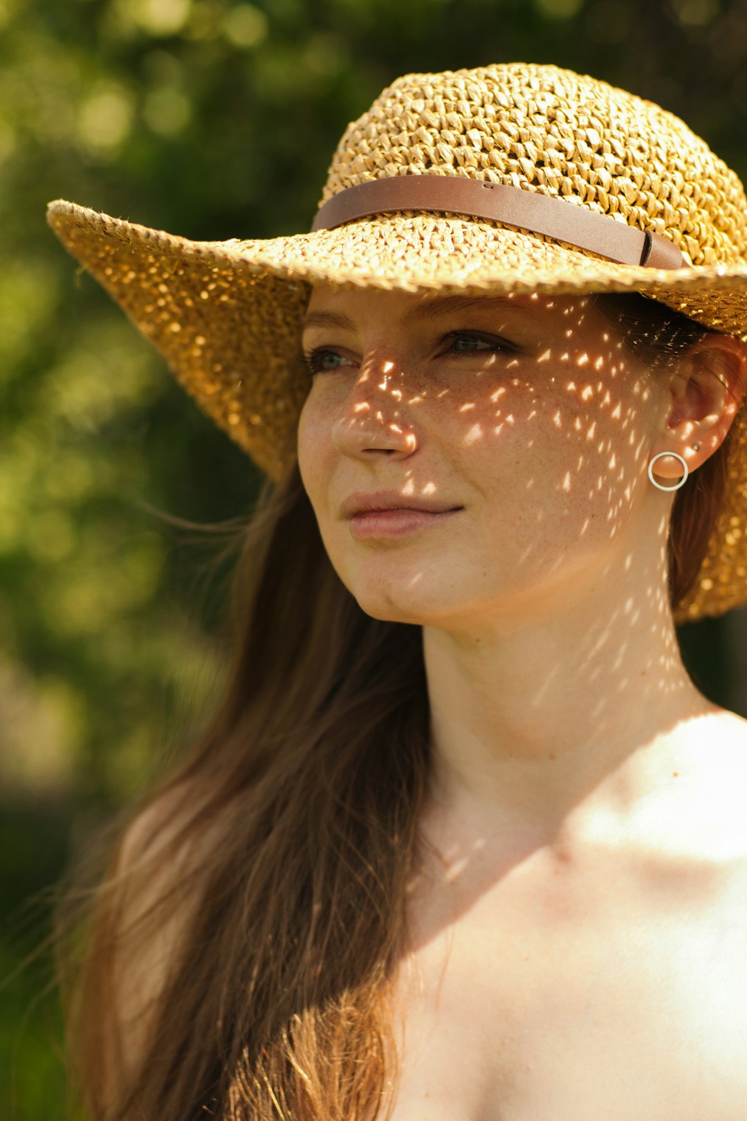 portrait of woman wearing off-shoulder top and beige sunhat