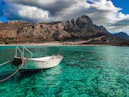 A small white boat anchored in the turquoise water at Balos Beach
