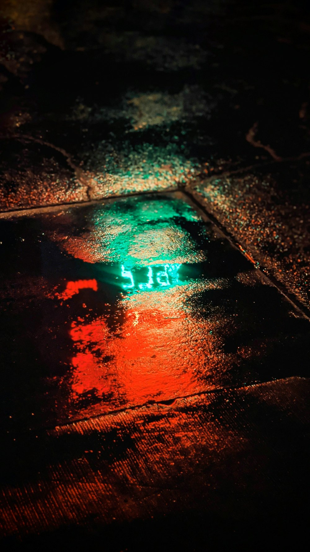 a green street sign sitting on the side of a wet road