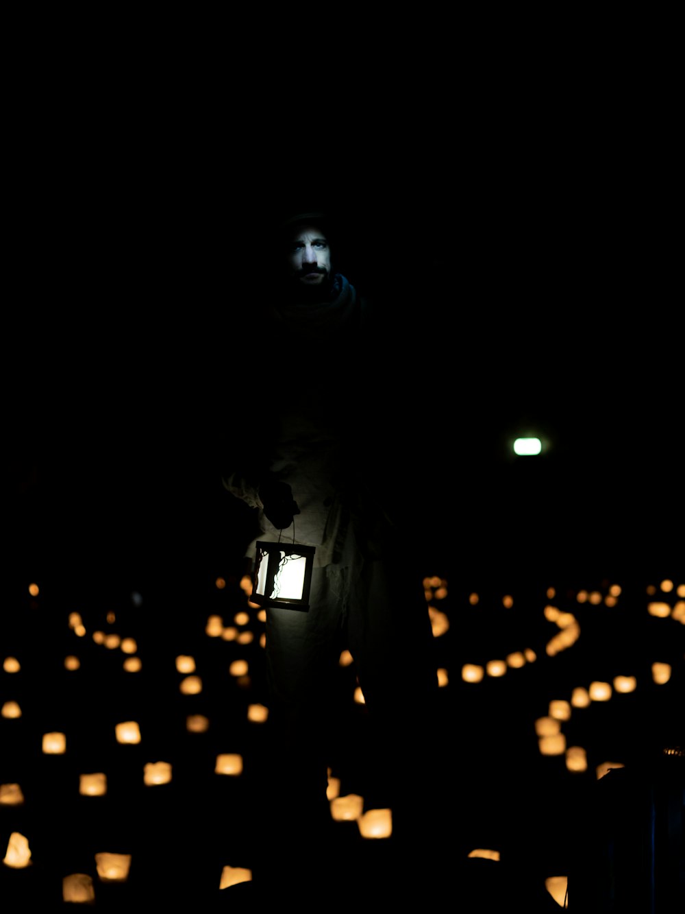 a man standing in the middle of a field of paper lanterns