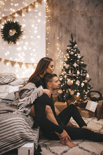 couple sitting beside Christmas tree
