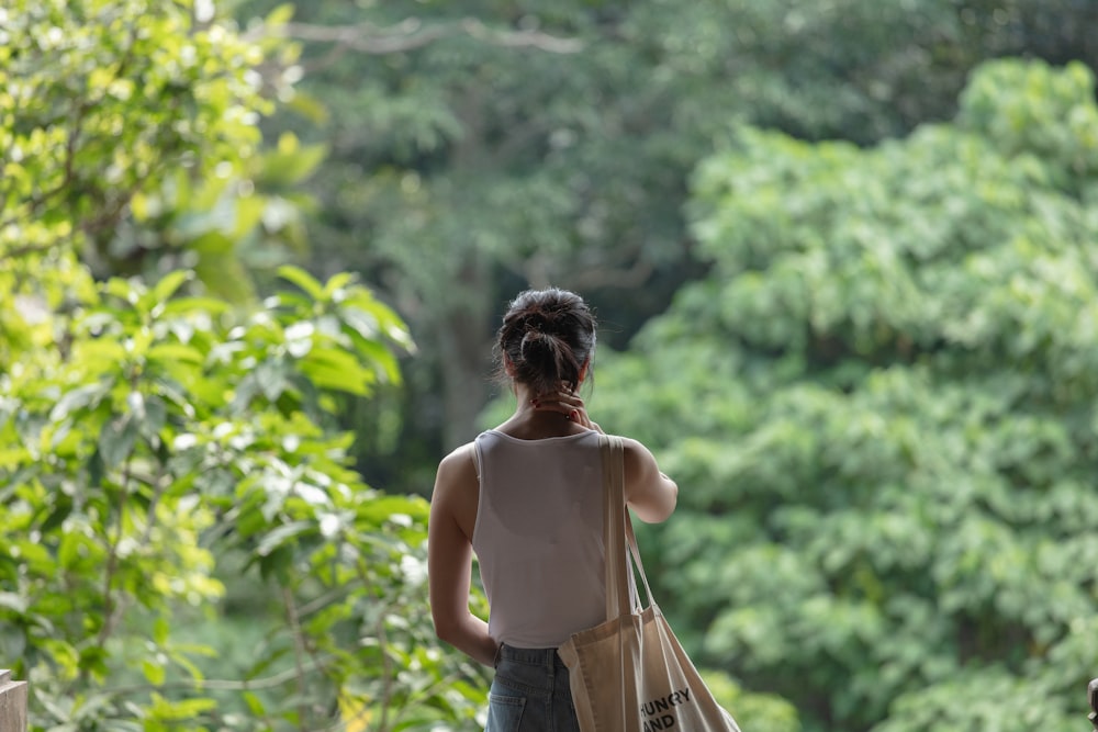 woman in white top standing near trees