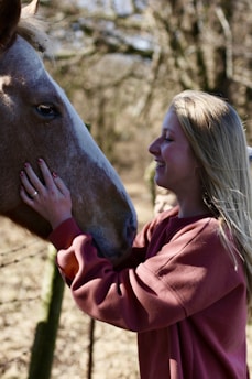 A therapist supporting a person with disabilities during a horse riding therapy session in a peaceful natural setting.