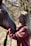 A smiling young participant gently grooming a horse in a sunny paddock.