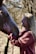 A person with long blonde hair is smiling while gently touching the face of a brown horse. They appear to be in a natural outdoor setting with blurred trees in the background.