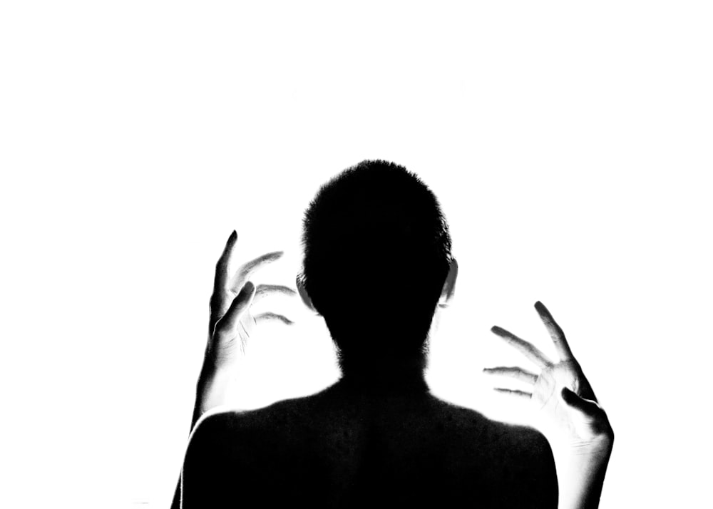a silhouette of a person holding their hands up