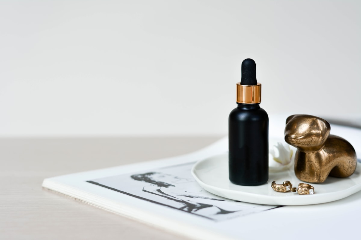 A dark glass dropper bottle standing on a pale surface
