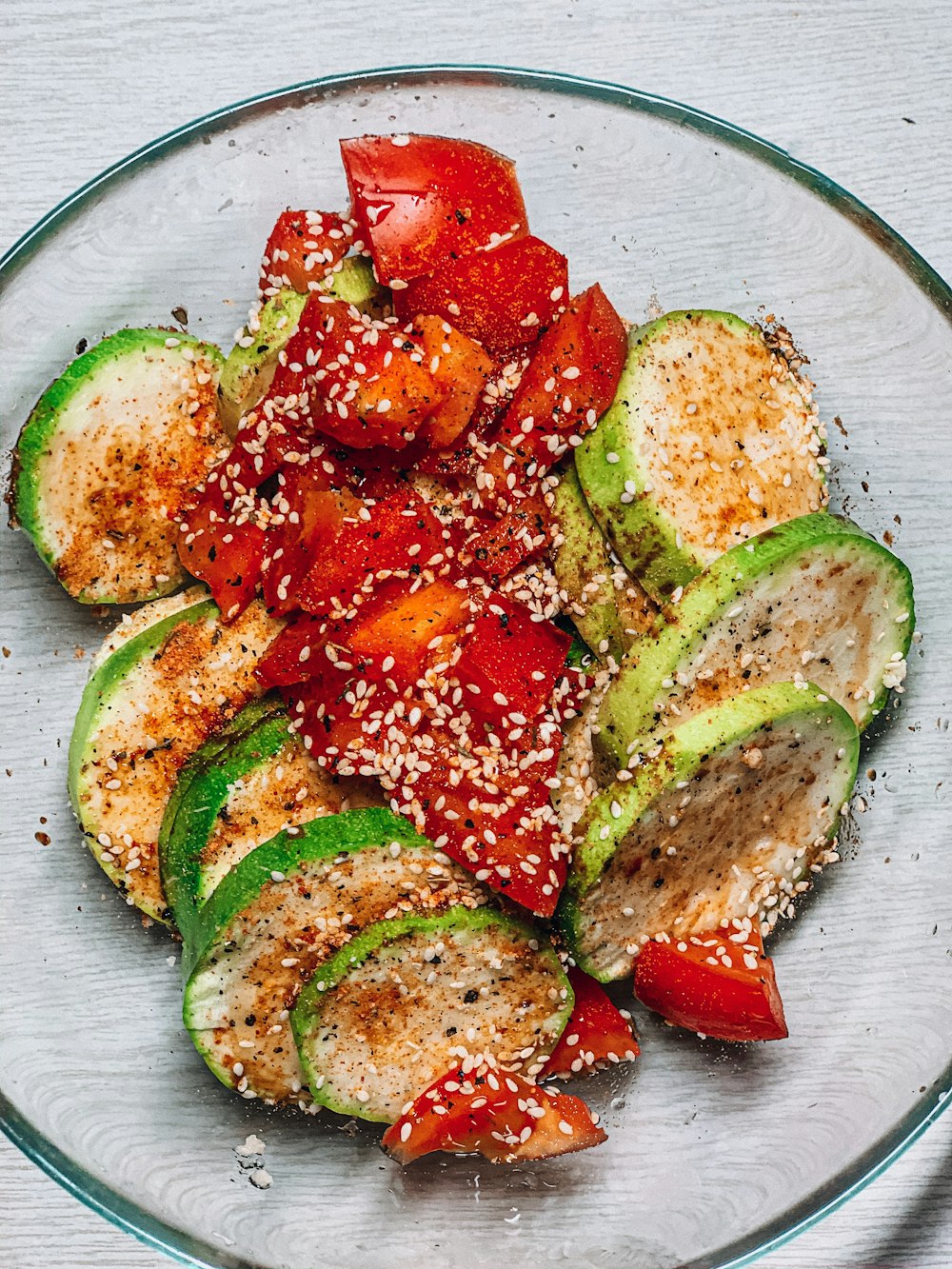 a glass plate filled with sliced up zucchini and tomatoes