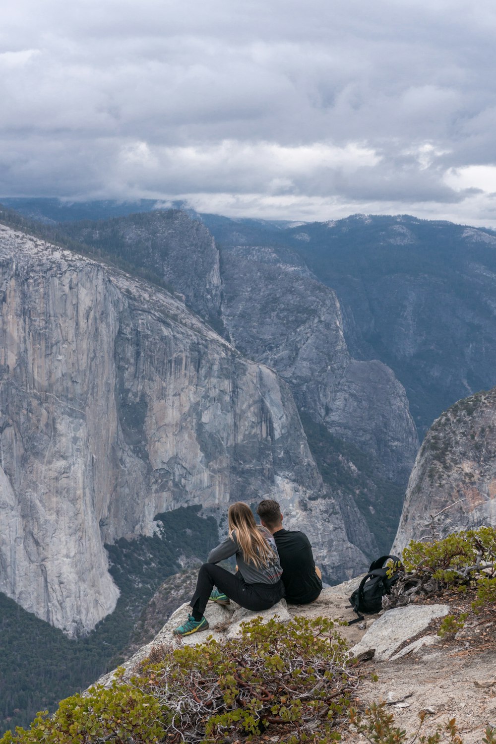 two person sitting on mountain during daytime