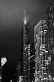 Black and white photo of city skyscrapers piercing through fog.