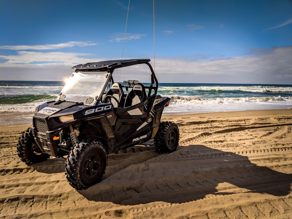 black UTV on sand near seashore