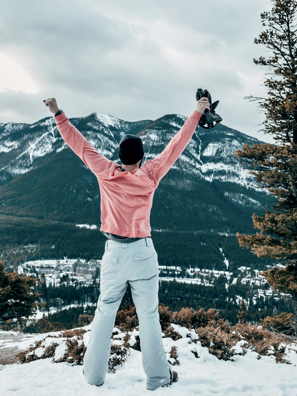 view photography of man standing on mountain while arms open wide during daytime