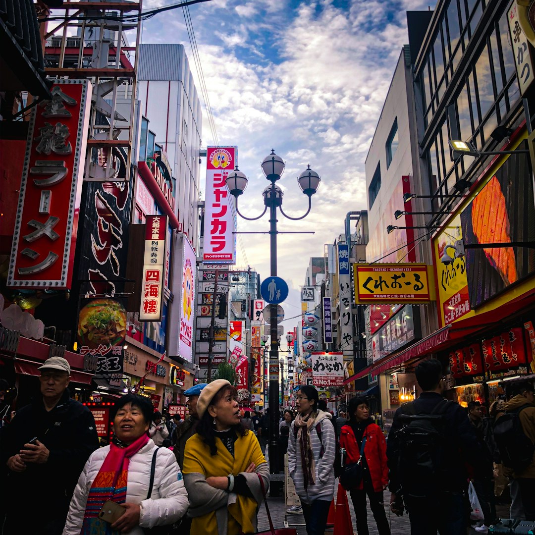 people walking on street near buildings under white and blue sky during daytime