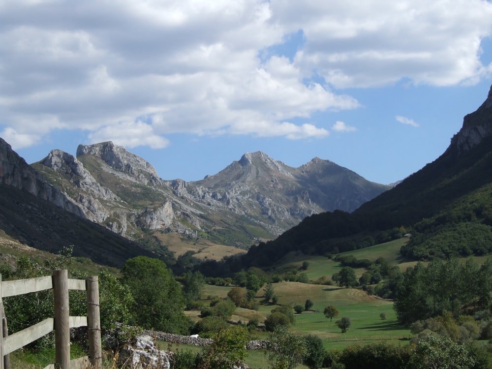 Fotografía aérea de campo verde que ve la montaña bajo el cielo blanco y azul durante el día