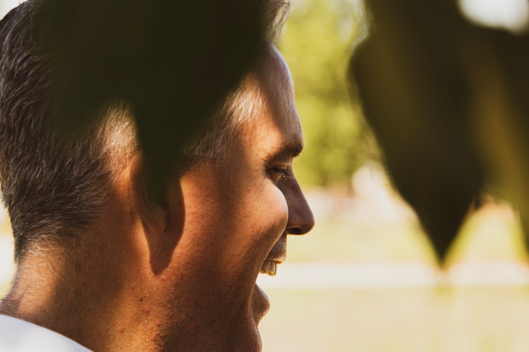 man wearing white top facing his right side laughing