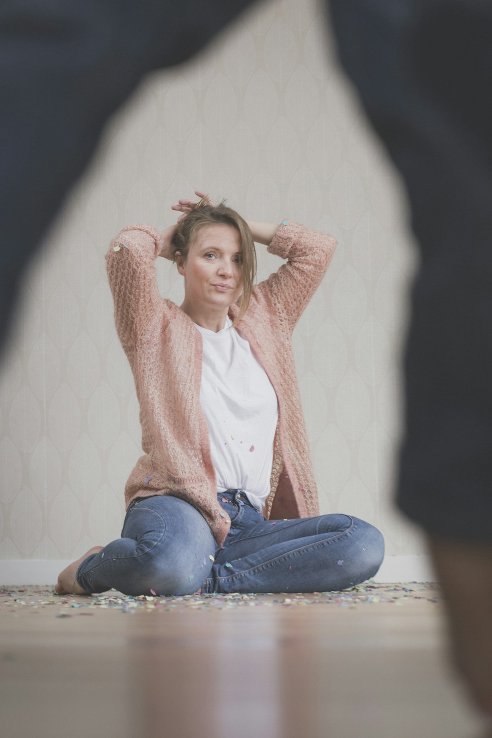 woman wearing beige sweater sitting while fixing her hair
