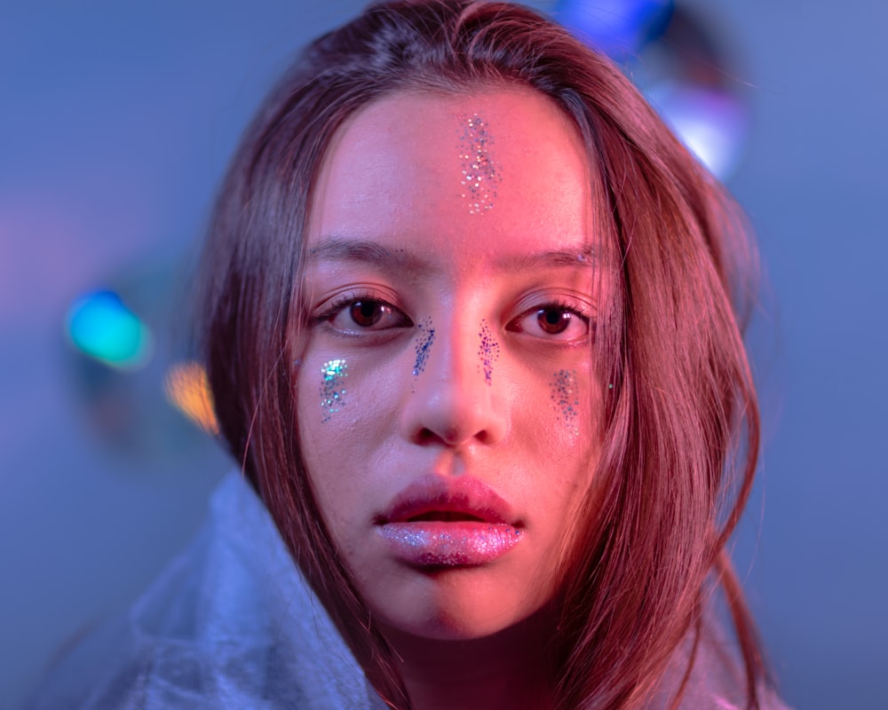 woman wearing white top with multicolored glitters on her face