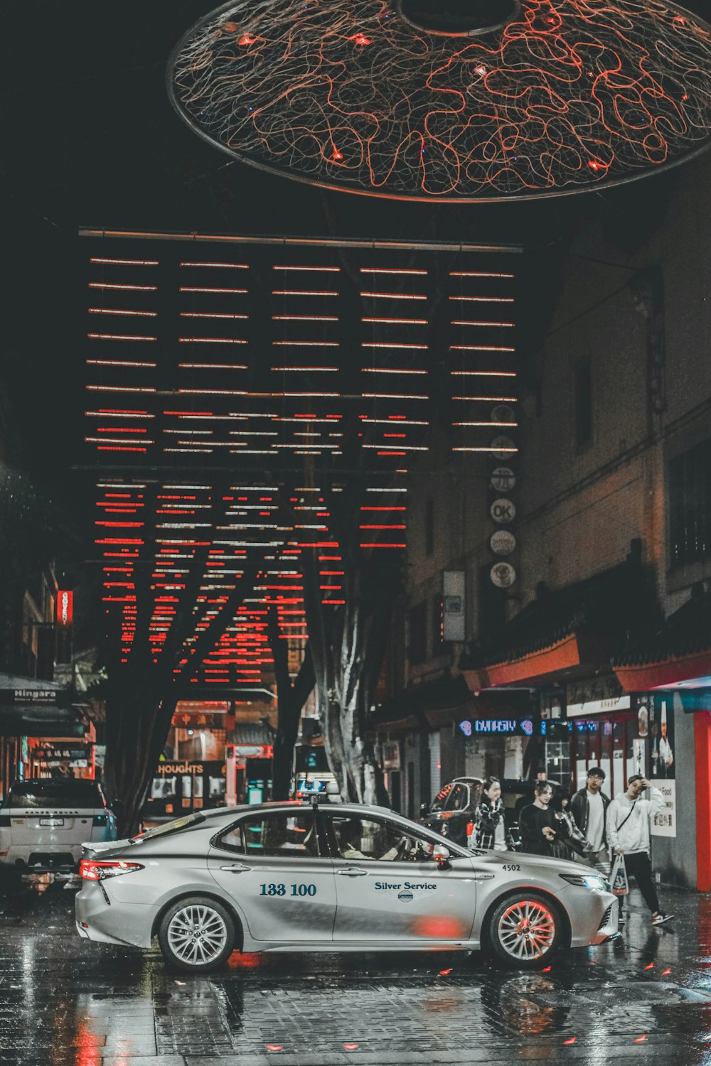 gray sedan parking near road and people walking on street during night time