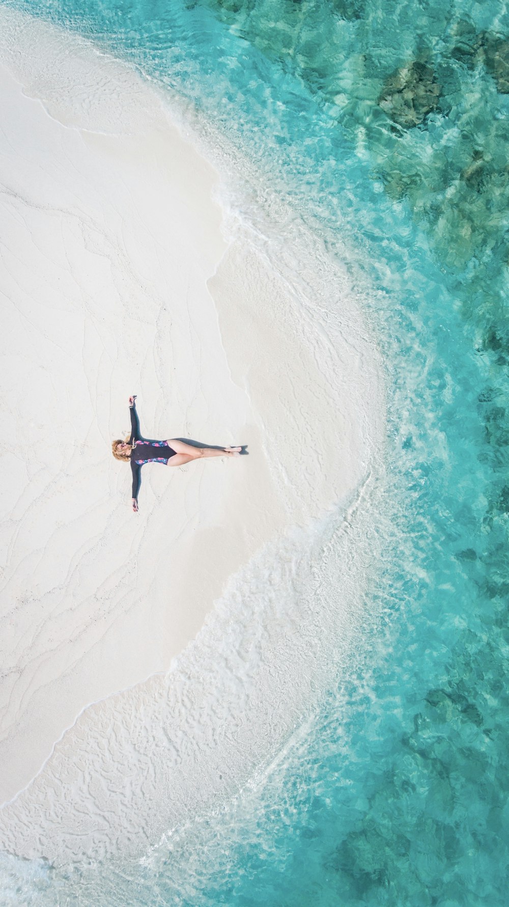 mujer acostada sobre arena blanca