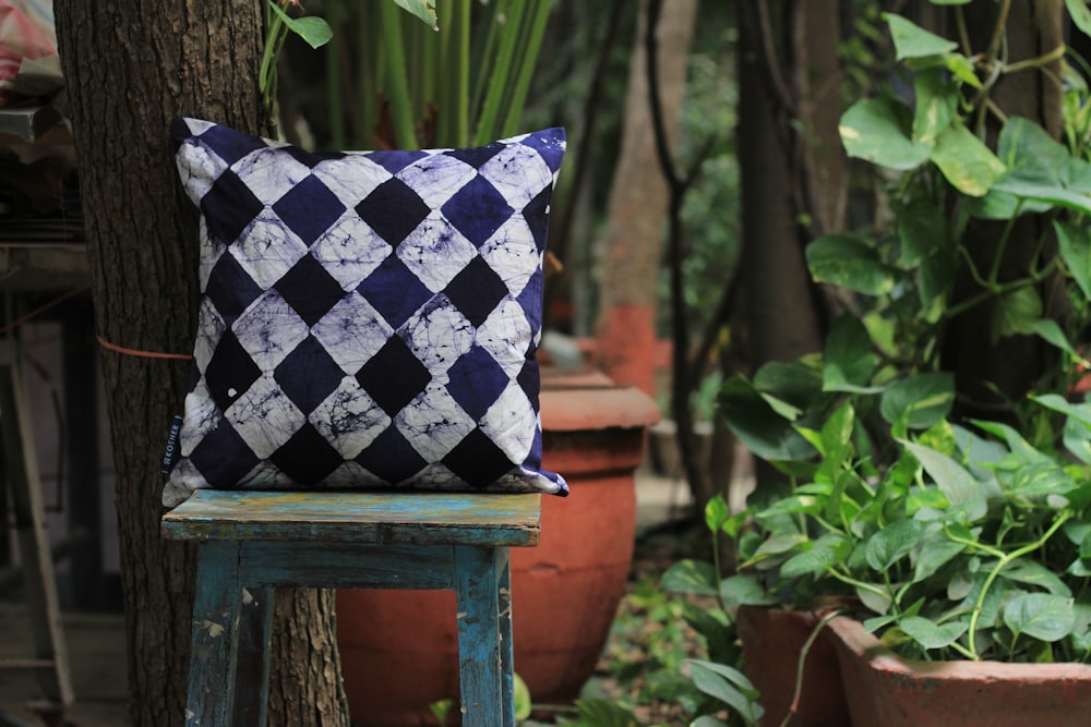 white, black, and purple harlequin throw pillow on square stool