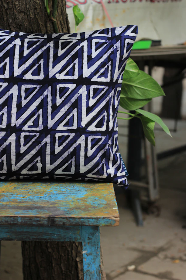 white, purple, and black throw pillow on teal and brown wooden bench