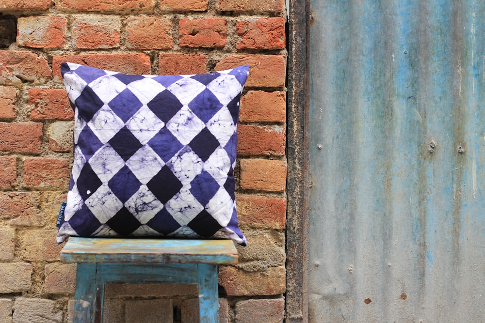 white, purple, and black harlequin throw pillow on stool