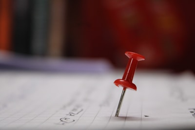 A close-up photo of a handwritten note pinned with a colorful magnet.