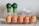A row of brown eggs displayed in a transparent plastic tray, each egg has a different expressive face drawn on it with black marker. The background features two green-capped spice bottles and a clear dish containing a white substance, possibly sugar or salt.