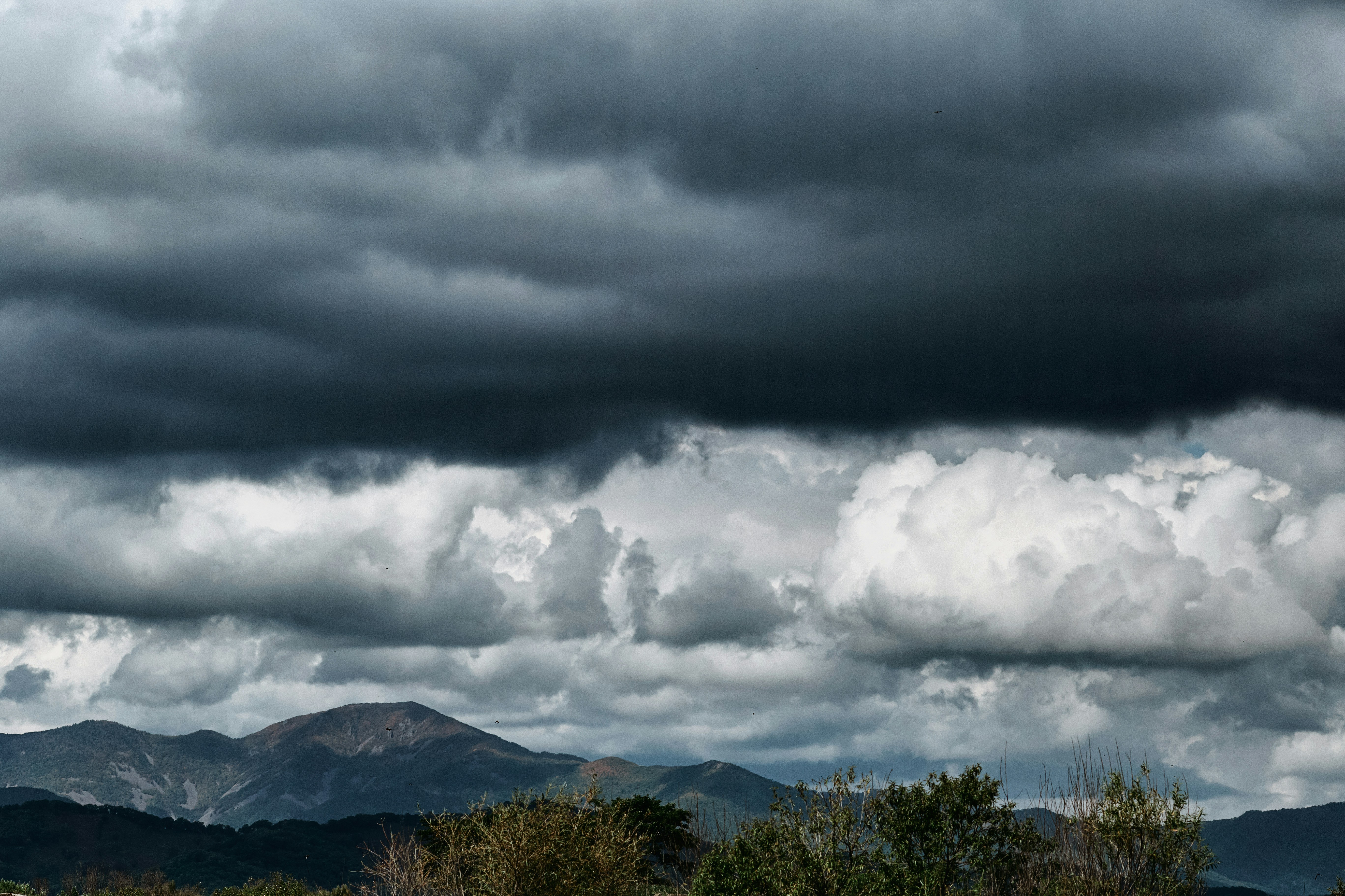 Gloomy cumulus clouds over the ridge. Summer atmospheric photo with rocks and sky.