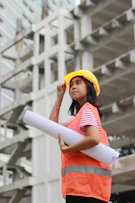woman smiling and holding floor plan near building during day