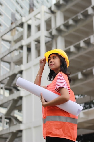 woman smiling and holding floor plan near building during day