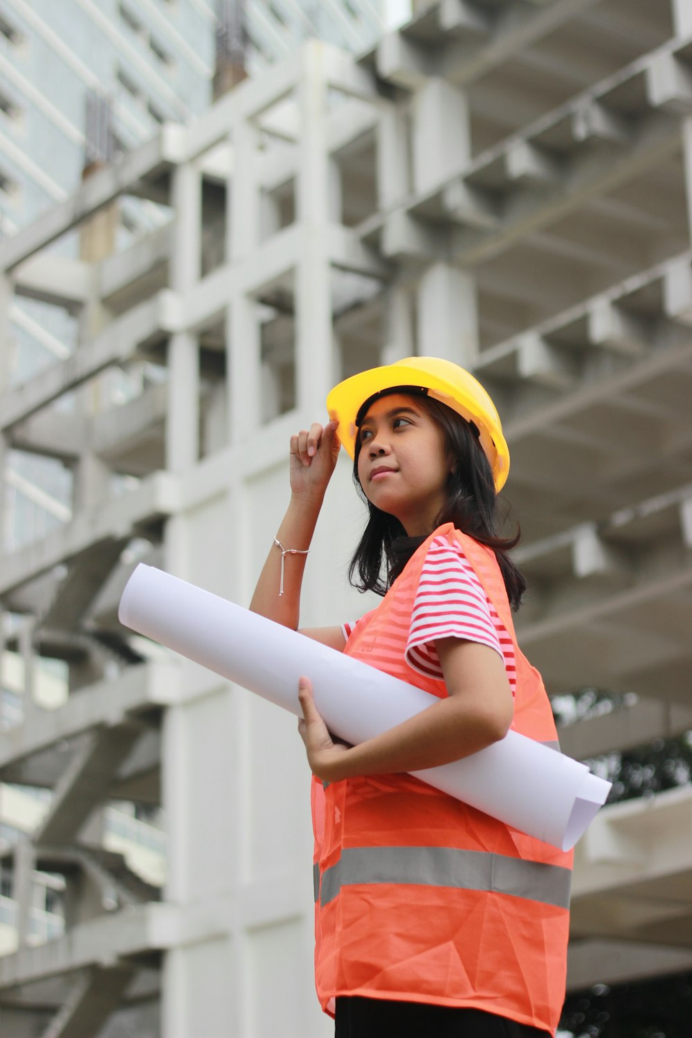 woman smiling and holding floor plan near building during day