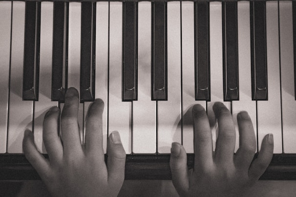 Close-up shot of pianist’s hands delicately pressing piano keys in monochrome.