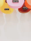 A collection of colorful ukuleles hanging against a rustic brick wall.