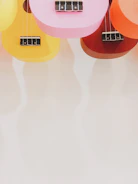 A collection of colorful ukuleles hanging against a rustic brick wall.
