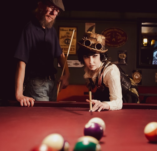 woman playing billiard near man